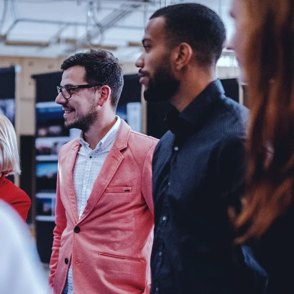 Two men listening intently and smiling.