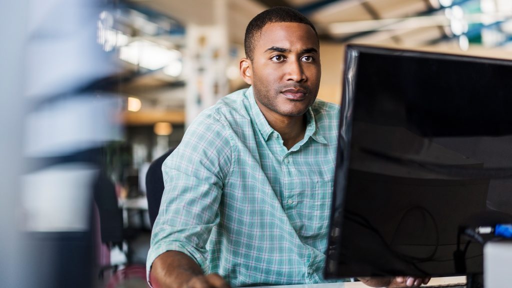 Man staring at screen. He is in an office environment.