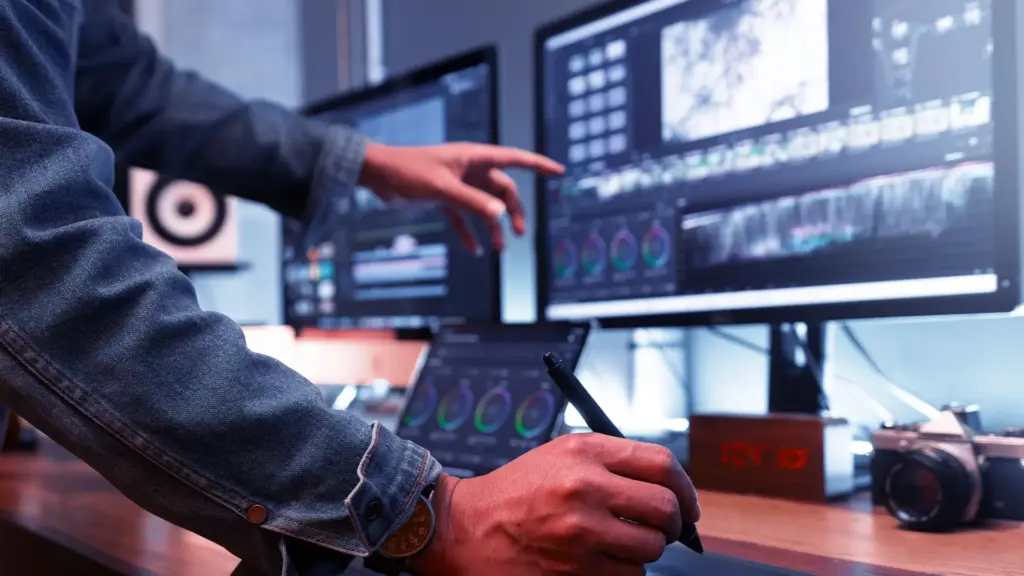 Person with pen in hand pointing to data filled computer screen.