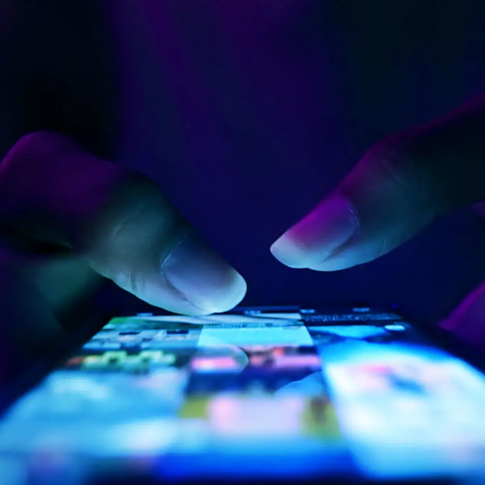 Top view of thumbs tapping on phone screen.