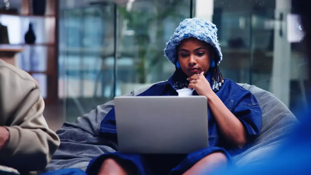 Woman sitting on beanbag staring at laptop.