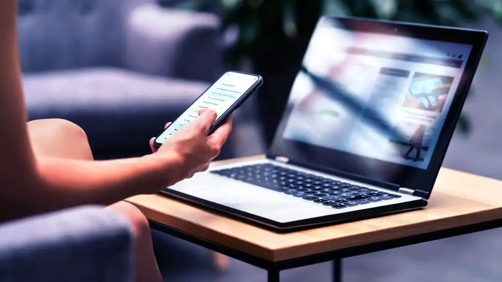 Mobile phone being held in front of laptop.