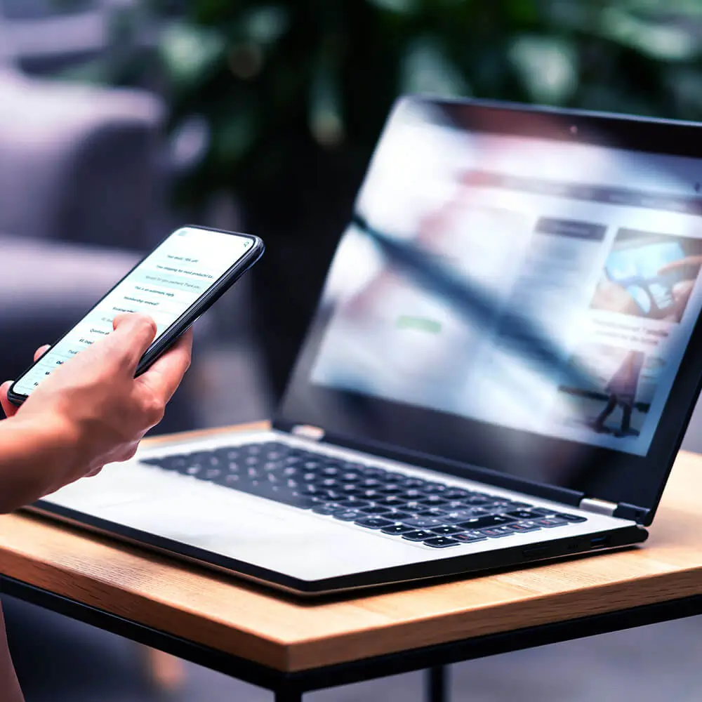 Mobile phone being held in front of laptop.