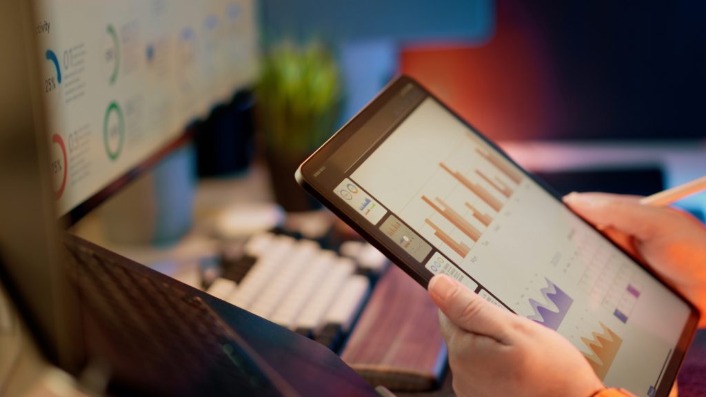 Person holding iPad tablet looking at graphs and data.