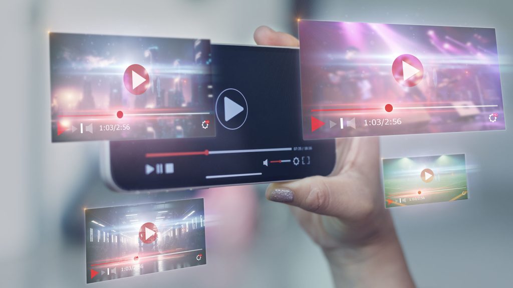 Futuristic image of person holding phone. Multiple holographic video screens surround the phone.