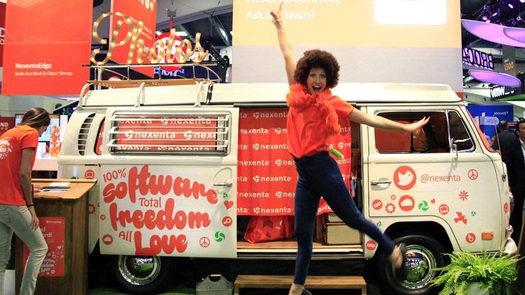 Person jumping in front of branded camper van.